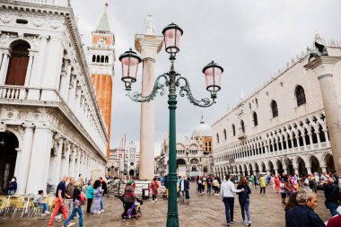 VENICE, ITALY - SEPTEMBER 24, 2019: people walking near saint mark bell tower and palace of Doge in Venice, Italy  clipart