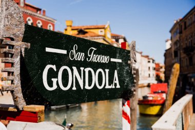VENICE, ITALY - SEPTEMBER 24, 2019: selective focus of signboard with san trovaso gondola lettering and ancient buildings on background in Venice, Italy  clipart