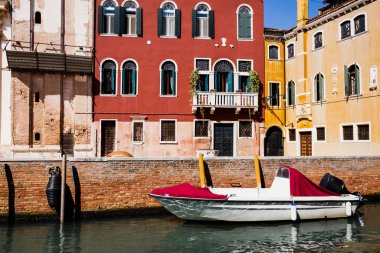 motor boat near bright and colorful buildings in Venice, Italy  clipart
