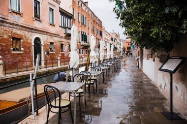 VENICE, ITALY - SEPTEMBER 24, 2019: outdoor cafe with view at canal and ancient buildings in Venice, Italy  clipart