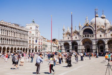 VENICE, ITALY - SEPTEMBER 24, 2019: tourists walking near Basilica of Saint Mark and clock tower in Venice, Italy  clipart