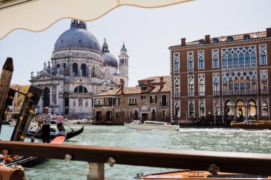 VENICE, ITALY - SEPTEMBER 24, 2019: motor boats and gondolas floating on canal near Santa Maria della Salute church  clipart