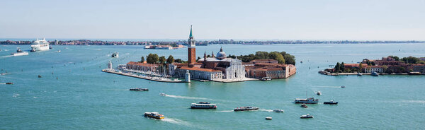 panoramic shot of San Giorgio Maggiore island and vaporettos floating on river in Venice, Italy 
