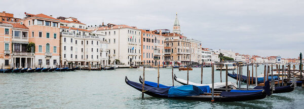 panoramic shot of canal with gondolas and ancient buildings in Venice, Italy 