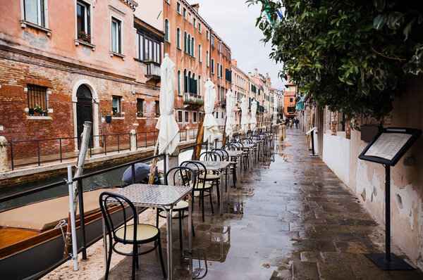 VENICE, ITALY - SEPTEMBER 24, 2019: outdoor cafe with view at canal and ancient buildings in Venice, Italy 