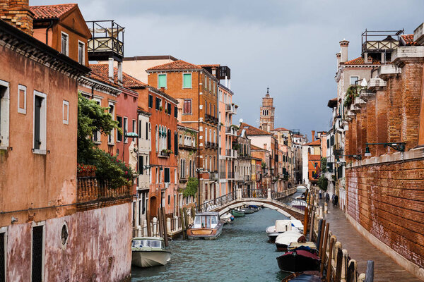 bridge above canal, motor boats and ancient buildings in Venice, Italy 