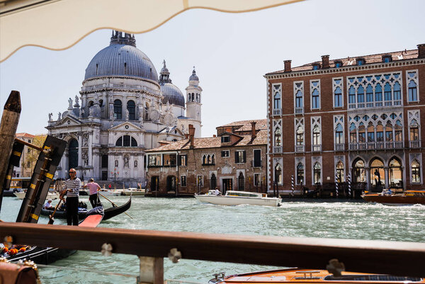 VENICE, ITALY - SEPTEMBER 24, 2019: motor boats and gondolas floating on canal near Santa Maria della Salute church 