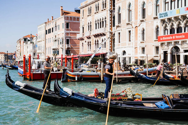 VENICE, ITALY - SEPTEMBER 24, 2019: side view of gondoliers floating on gondolas in Venice, Italy 