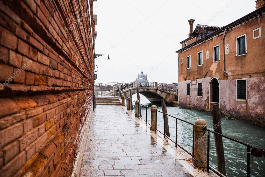 road along canal and ancient building in Venice, Italy 