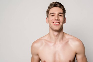 Güler yüzlü seksi adam, kaslı gövdesi griye bürünmüş.