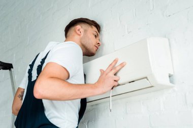 handsome worker installing air conditioner  clipart