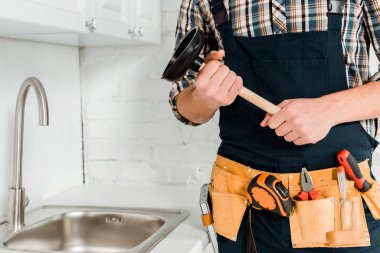 Lavabonun yanında lavabo pompası tutan tesisatçı manzarası. 