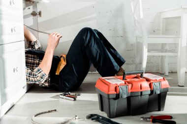 cropped view of installer lying on floor near tool box  clipart