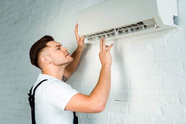 handsome installer looking at air conditioner 