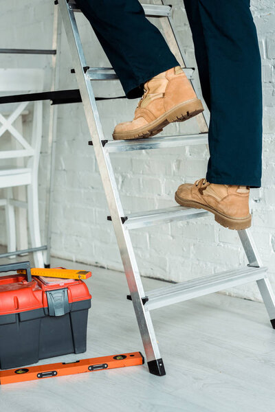 cropped view of installer climbing ladder near tool box 