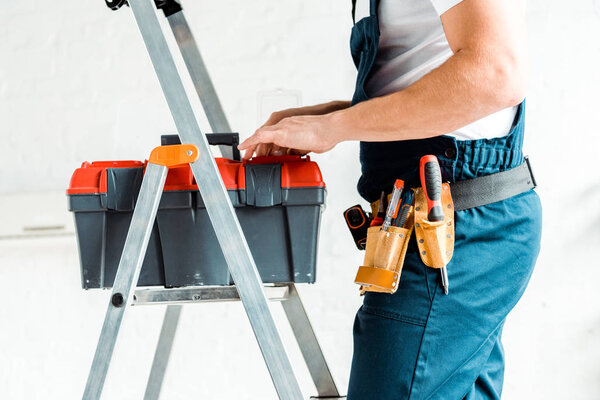 cropped view of installer standing on ladder and holding tool box 