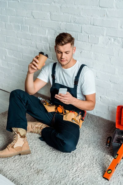Handsome Installer Using Smartphone While Holding Paper Cup — Stock Photo, Image