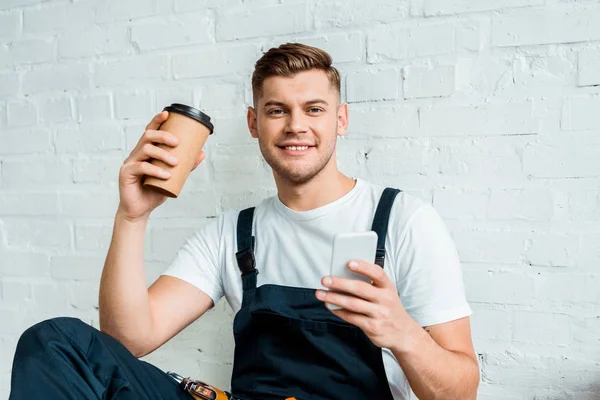 Cheerful Installer Using Smartphone While Holding Paper Cup — Stock Photo, Image