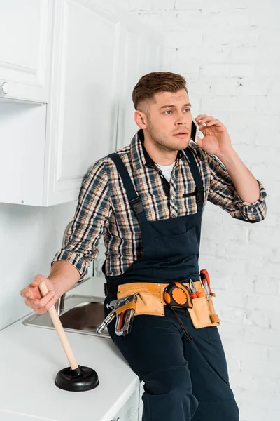 Handsome Installer Talking Smartphone While Holding Plunger — Stock Photo, Image