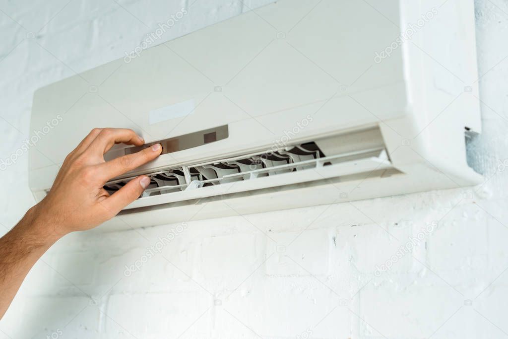 Cropped view of installer pushing buttons on air conditioner
