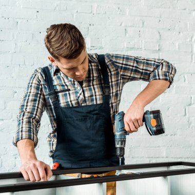 focused installer holding hammer drill near rack  clipart