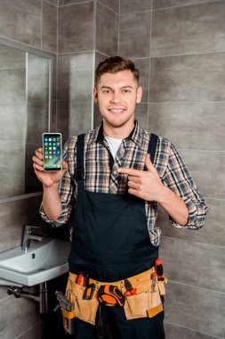 Kyiv, Ukrayna - 4 Aralık 2019: Banyodaki iPhone 'u işaret eden mutlu kurucu 