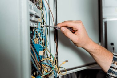 Elektrikçinin elinde tornavidayı santral yakınında tuttuğu kırpılmış görüntü  