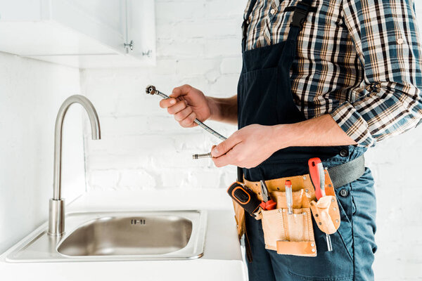 cropped view of installer holding metal hose near sink 