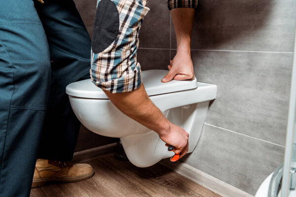 cropped view of installer standing near white toilet 