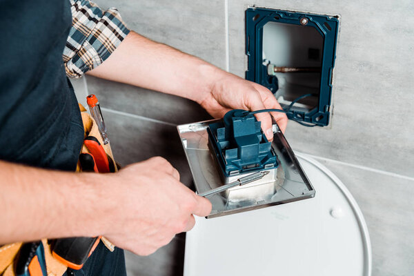 cropped view of workman holding screwdriver near toilet 