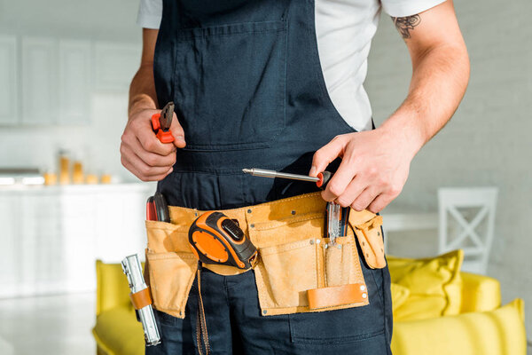 cropped view of installer standing and holding screwdriver and pliers 