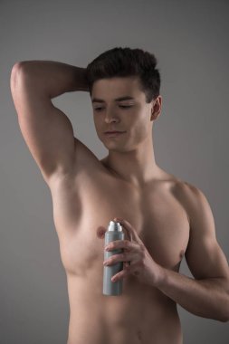 Deodorant tutan genç bir adam. Gri yolda, koltukaltı yakınlarında.