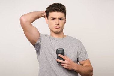 Gri tişörtlü, terli, koltuk altı deodorant tutan, gri tişörtlü, hoşnutsuz bir adam.