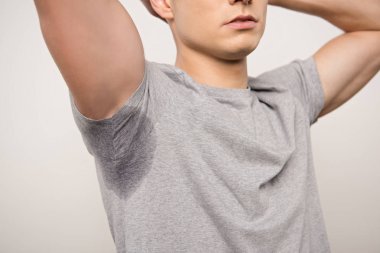 cropped view of young man in grey t-shirt with sweaty underarm isolated on grey clipart