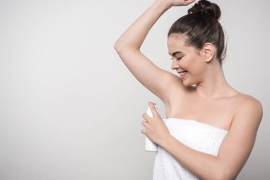 Gri renkte, koltuk altına deodorant süren neşeli genç bir kadın.