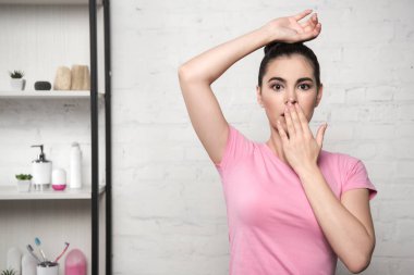 shocked woman covering mouth with hand while standing with raised hand clipart