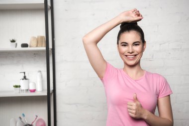 Elini kaldırıp kameraya gülümseyen mutlu bir kadın.