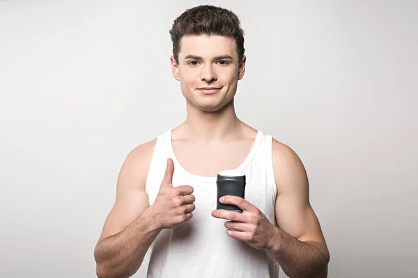 Smiling Man White Sleeveless Shirt Holding Deodorant Showing Thumb Isolated — 스톡 사진