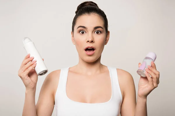 Podekscytowana Kobieta Patrząc Kamerę Trzymając Dezodoranty Odizolowane Szaro — Zdjęcie stockowe