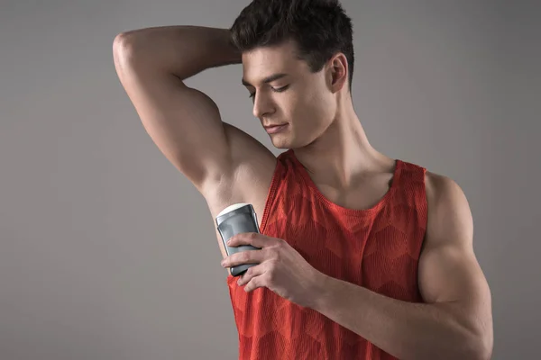 Young Man Red Sleeveless Shirt Applying Deodorant Underarm Isolated Grey — Stock Photo, Image
