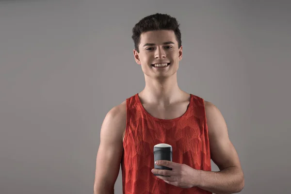 Gri Renkli Kameraya Gülümserken Elinde Deodorant Tutan Kırmızı Kolsuz Genç — Stok fotoğraf