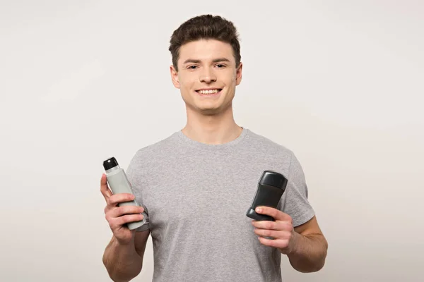 Young Man Grey Shirt Holding Deodorants Smiling Camera Isolated Grey — Stock Photo, Image