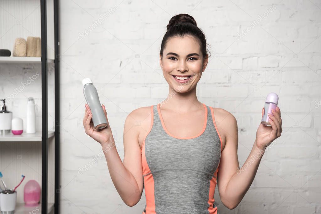 cheerful woman smiling at camera while holding deodorants