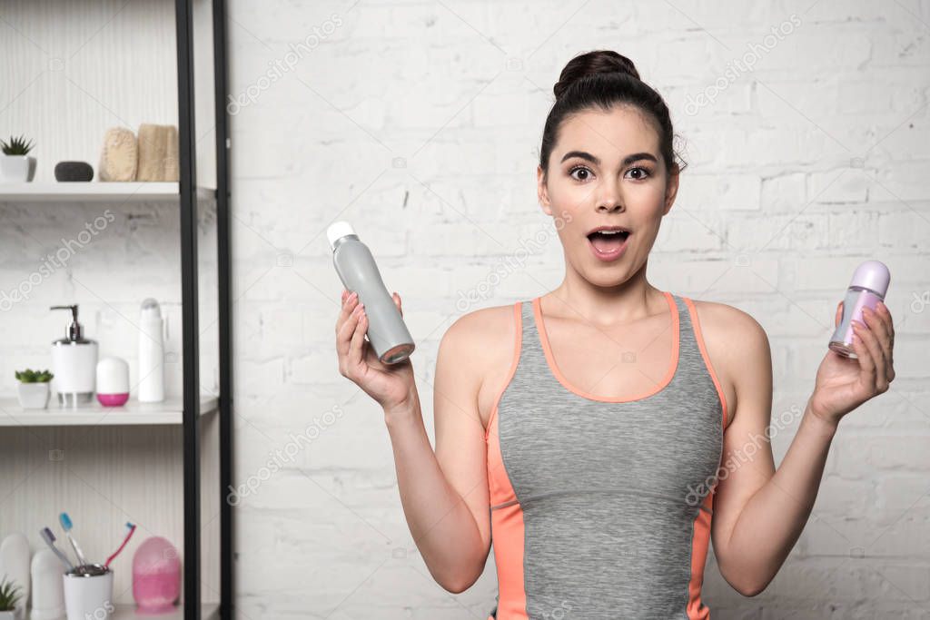 excited woman looking at camera while holding deodorants