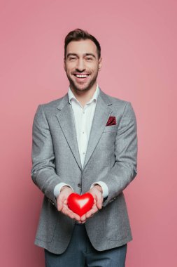 Sevgililer günü için kırmızı kalbi tutan yakışıklı, pembe bir adam. 