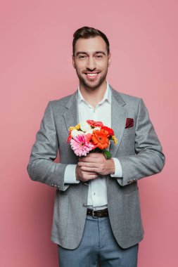 Çiçek buketi tutan gülümseyen adam, pembe üzerinde soyutlanmış.