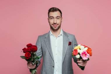 Sakallı, takım elbiseli, elinde pembe bir buket tutan adam.