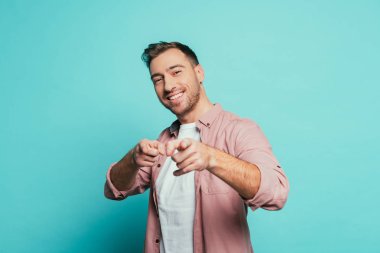 cheerful handsome man pointing at you, isolated on blue