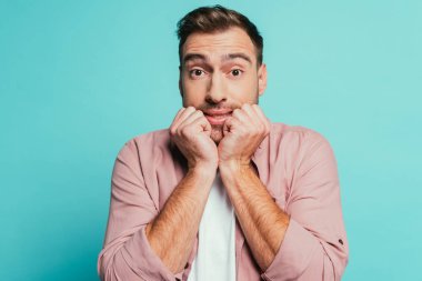 Korkmuş yakışıklı adam mavi üzerine izole edilmiş el kol hareketi yapıyor.