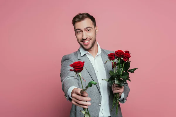 Mooie Positieve Man Pak Met Rode Roos Bloemen Geïsoleerd Roze — Stockfoto